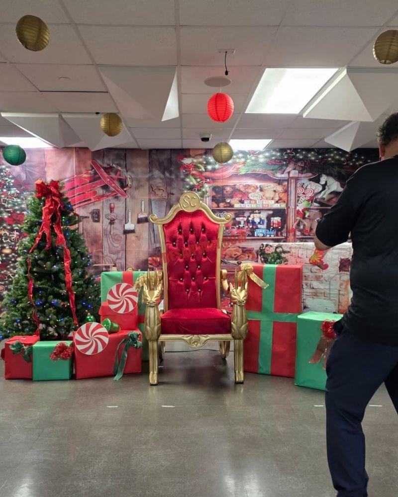 Santa photo session setup in New York City: empty gold chair with reindeer armrests, gifts, and a tree
