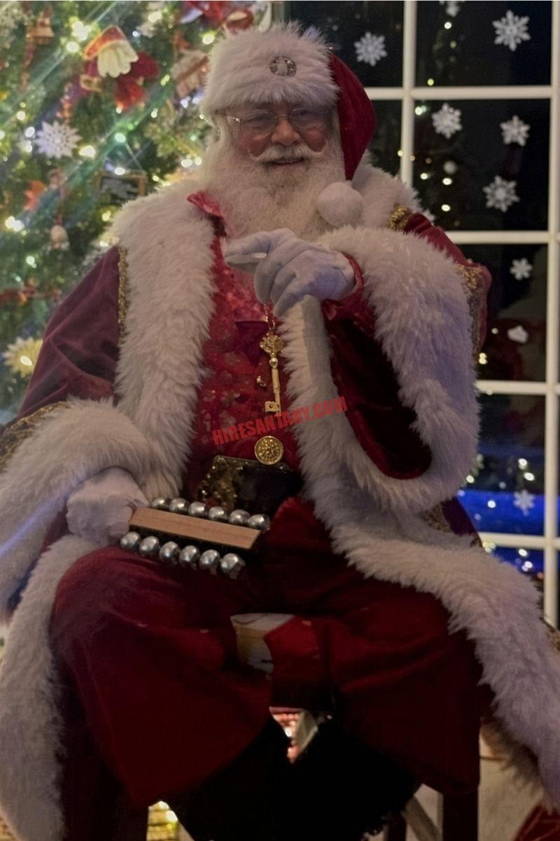 Santa house call in Queens, NY: Santa with sleigh bells beside a tree and a night window